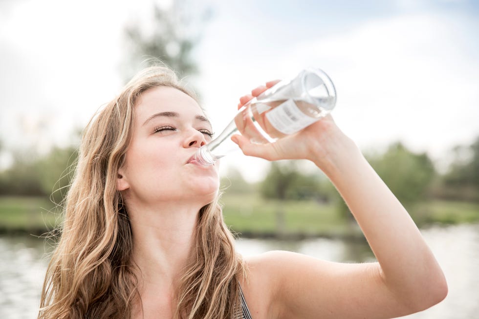 young woman drinking water from bottle, outdoors