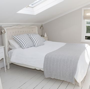 Bed in whitewashed attic bedroom