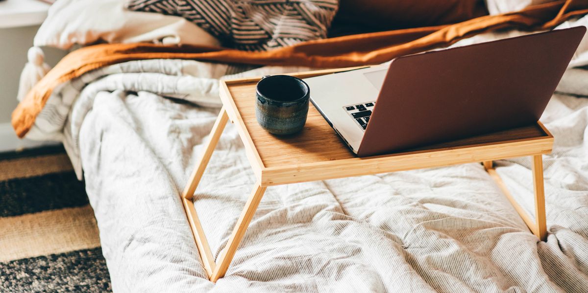 laptop and mug on wooden tray in bed