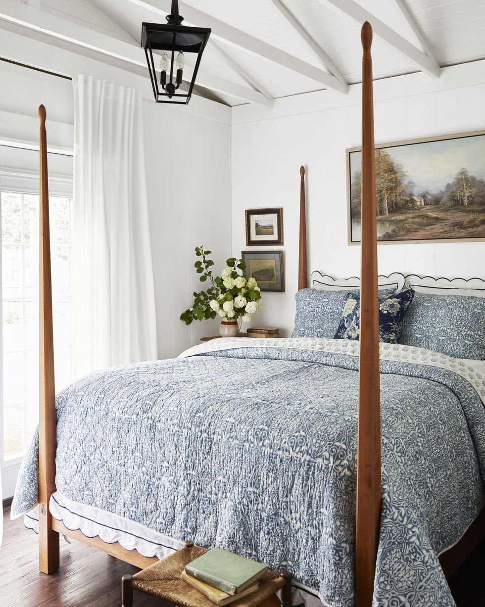 consistent color scheme of blue and white used throughout the house the pairing is layered in the primary bedroom through a series of pretty prints on the pencil post bed she found online