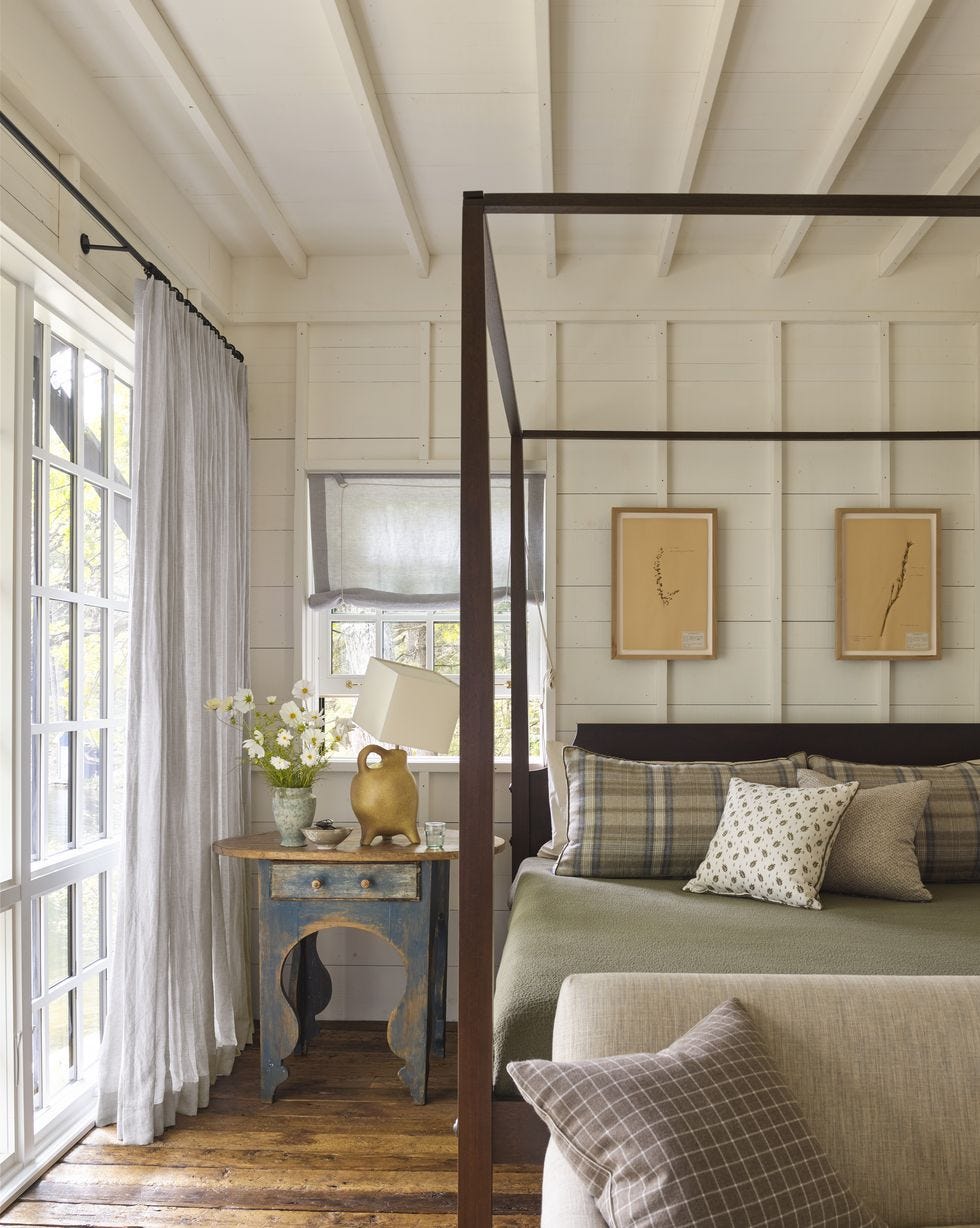 a mountain house bedroom with plaid pillows and a grid of artwork