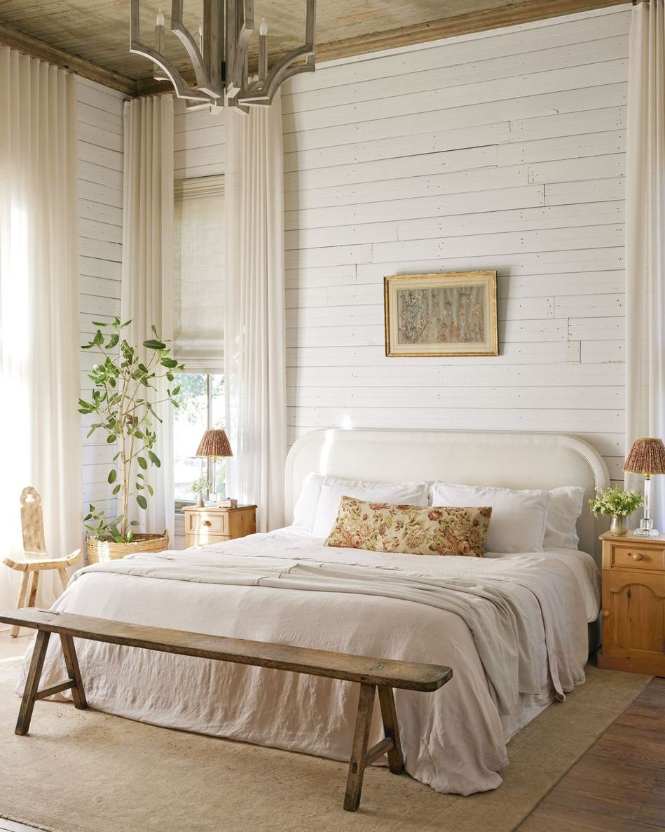 in the primary bedroom the homeowner softened the homes rustic edges with linen draperies that reach up to the 11 foot high ceilings then puddle to the floor