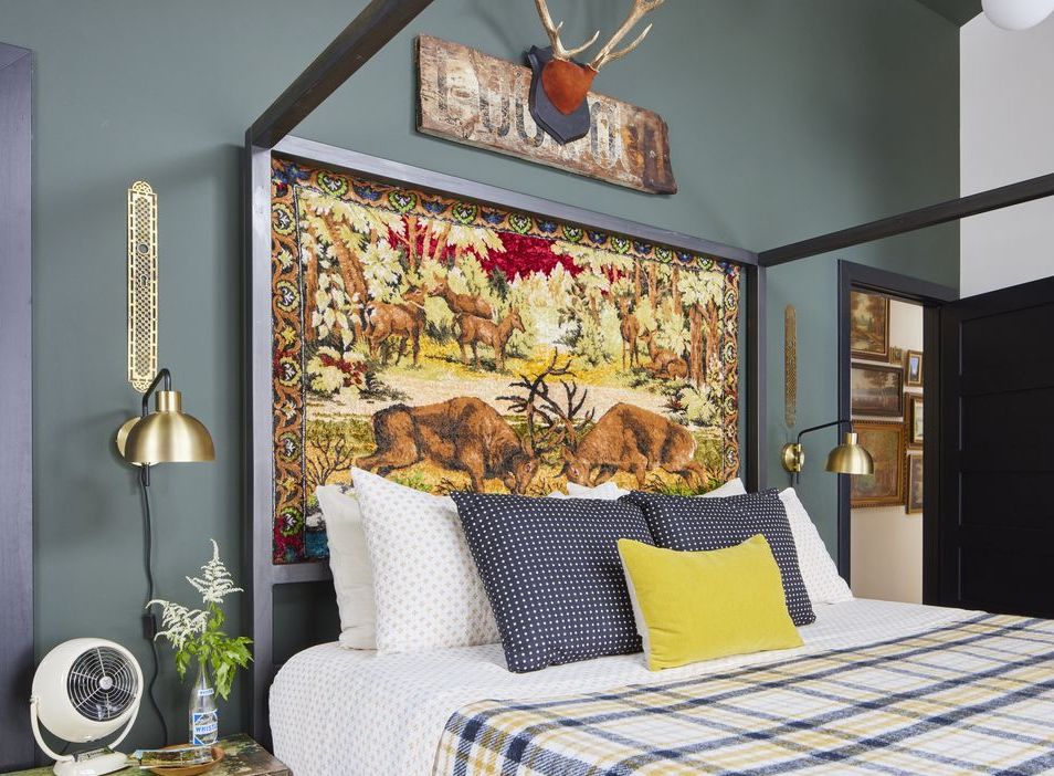 a vintage wildlife themed tapestry stands in as the headboard in the primary bedroom