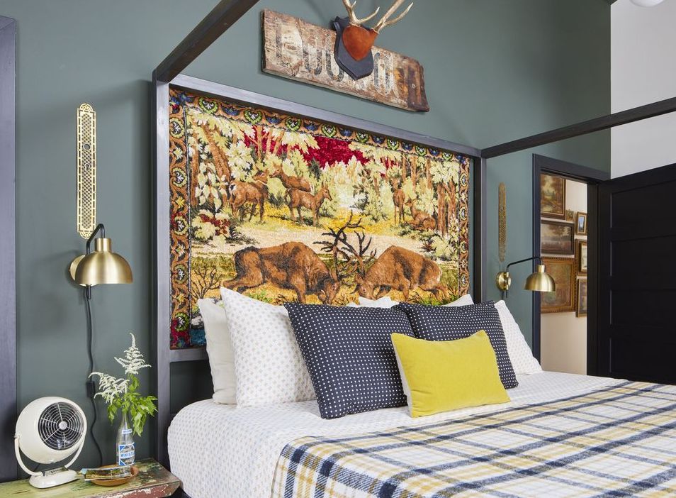 a vintage wildlife themed tapestry stands in as the headboard in the primary bedroom