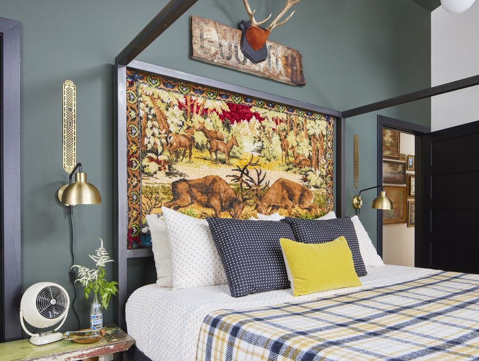 a vintage wildlife themed tapestry stands in as the headboard in the primary bedroom