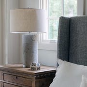 This is an image cement bedroom lamp next to grey bed