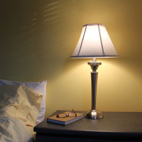 ランプ、本、老眼鏡を備えた寝室のナイトテーブル