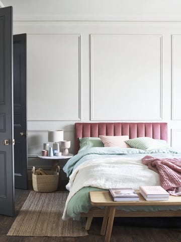 dormitorio elegante con cabecero tapizado y pared panelada