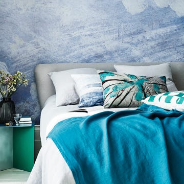 bedroom with a painted mural on the wall behind the double bed blue bed