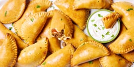 golden brown beef filled empanadas with a creamy dipping sauce