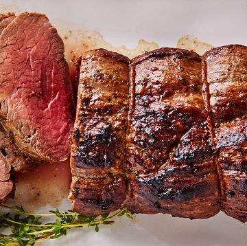 beef tenderloin sliced on a white platter served with rosemary