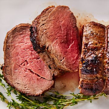 beef tenderloin sliced on a white platter served with rosemary