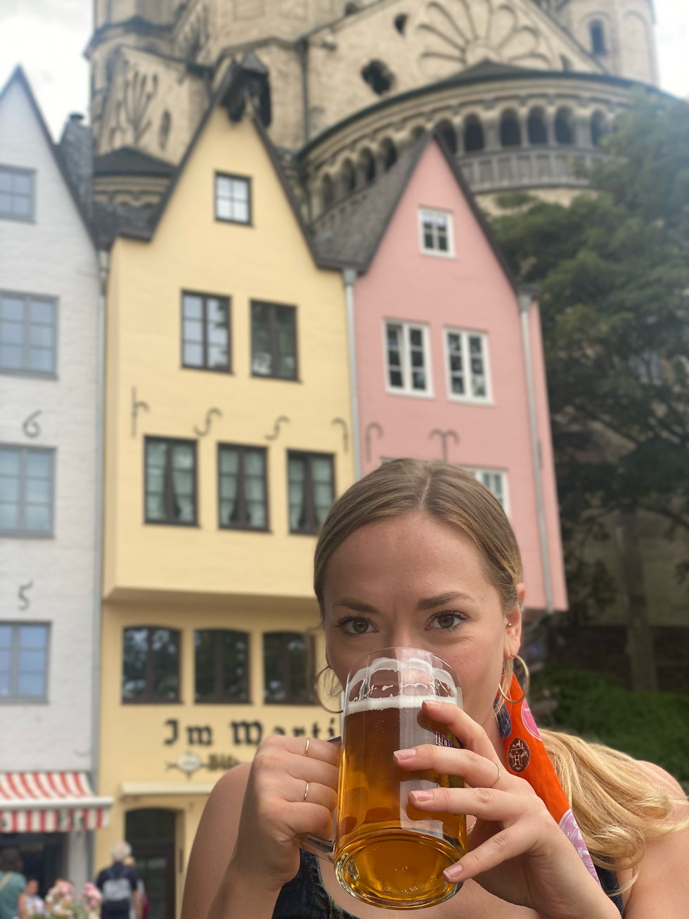 individual holding a large beer mug in front of colorful buildings