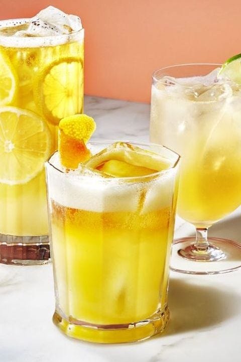 a yellow beer cocktail with an orange rind on garnished on top
