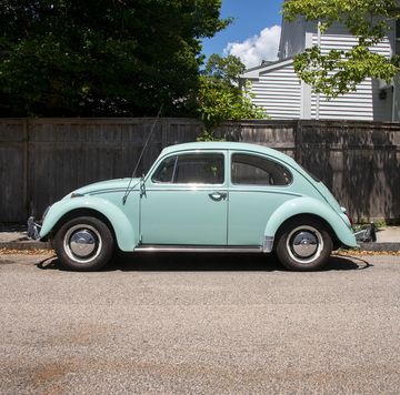 a 1966 vw beetle 1300 parked on the side of the road