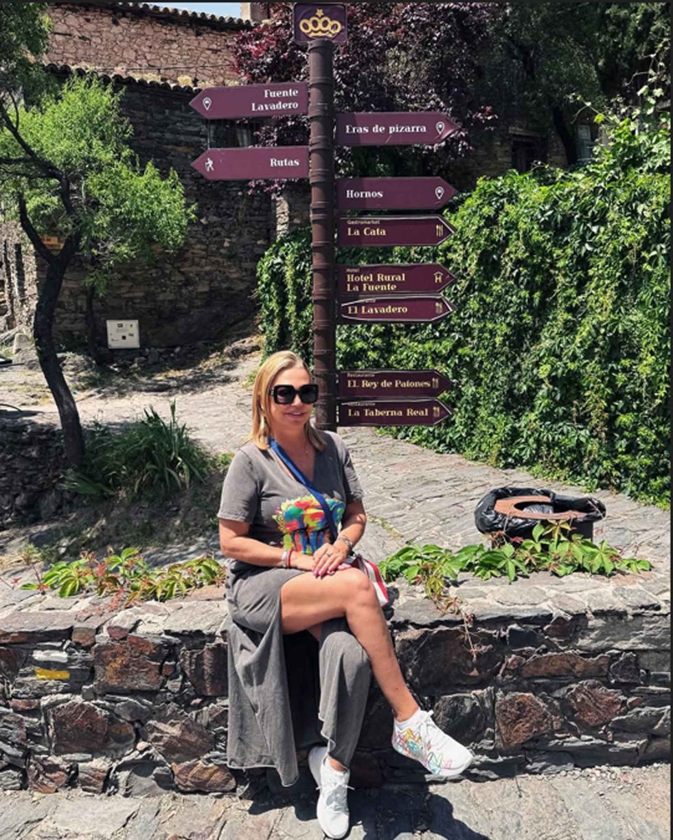 a woman resting by a directional sign in a scenic location