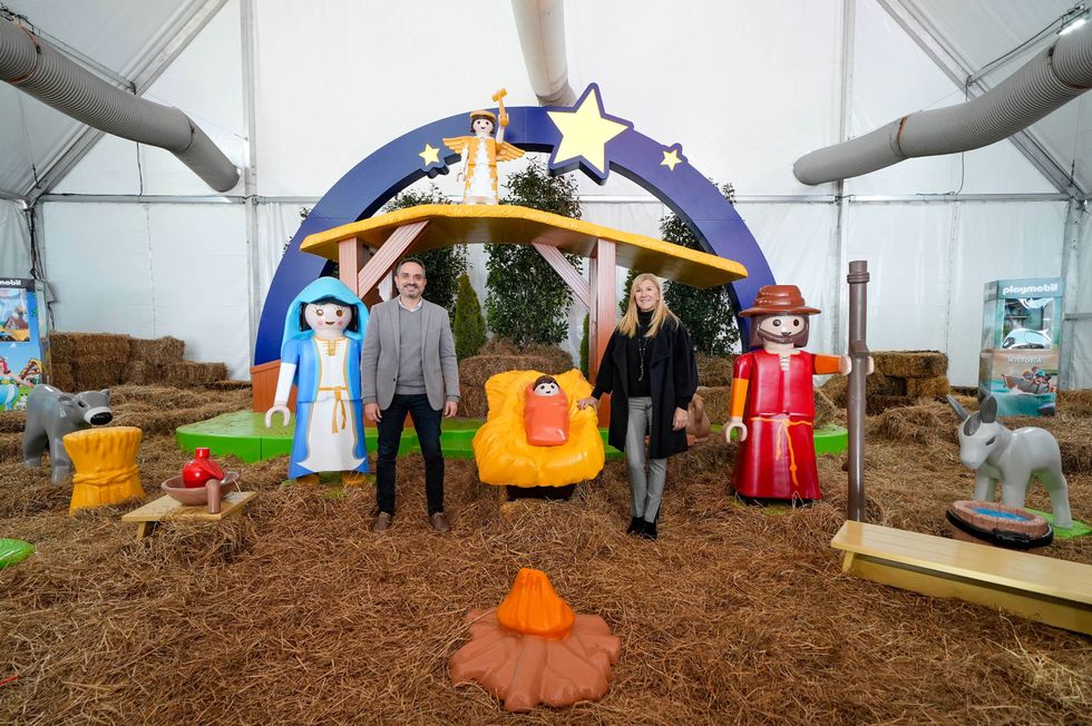 a couple of people standing in front of a tent with pumpkins and a statue