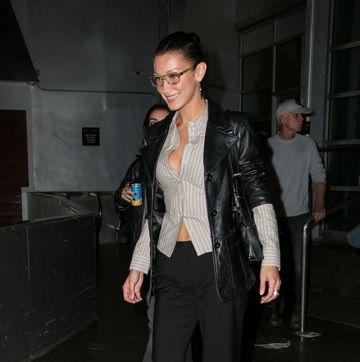 bella hadid siren trend style she is wearing aviator glasses a stripped grey shirt and a rolled up black leather jacket