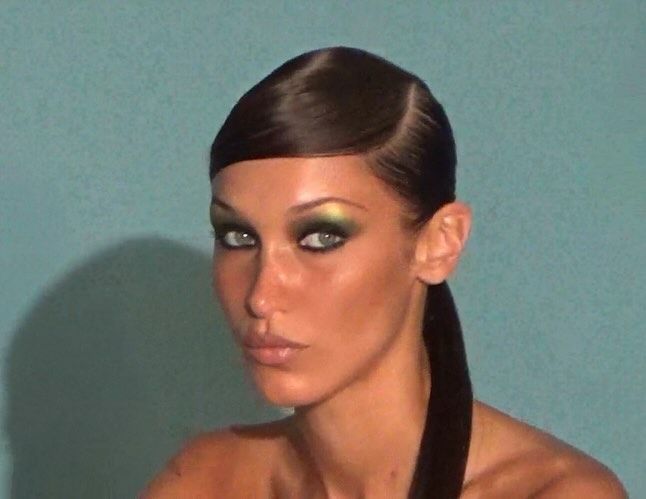 bella hadid poses with side parted ponytail and green eyeshadow