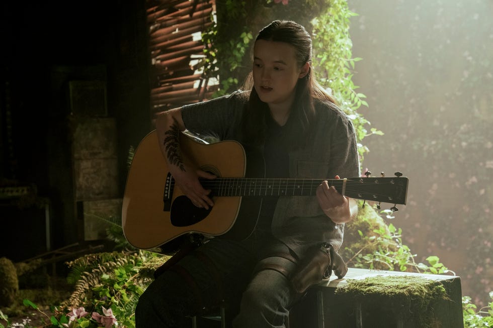 Persona tocando la guitarra acústica en un entorno natural con vegetación.
