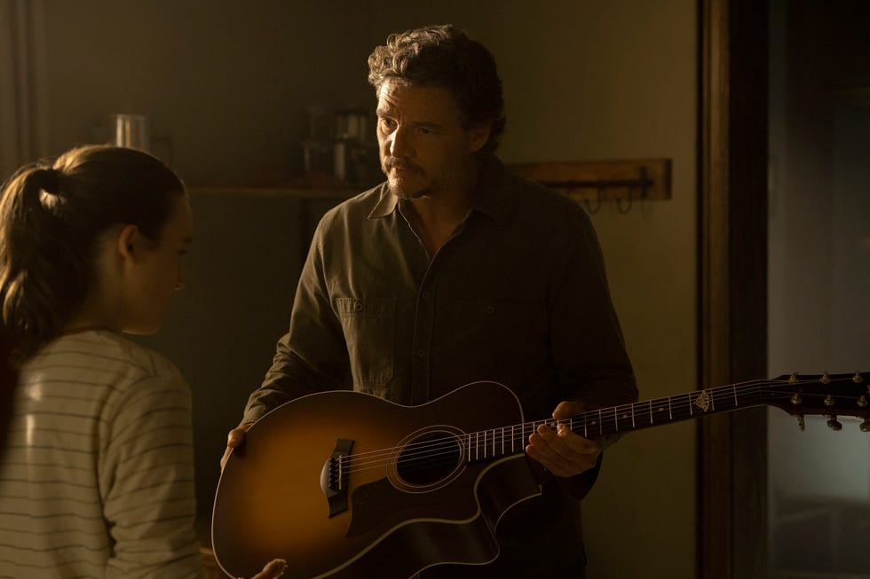 a person holding a guitar while speaking with someone else