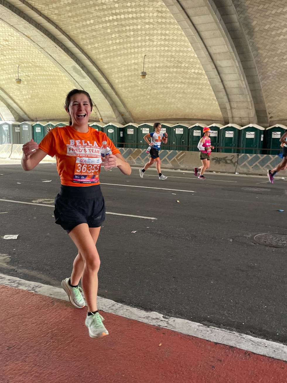runner in the nyc marathon wearing the hoka mach x sneakers and an orange shirt for charity