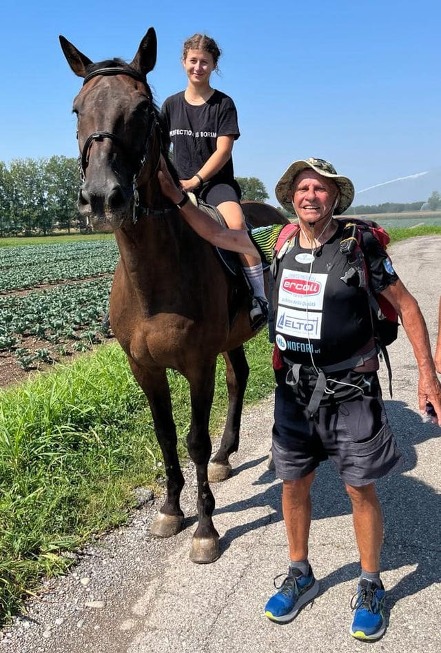 a man and a woman walking a horse on a path
