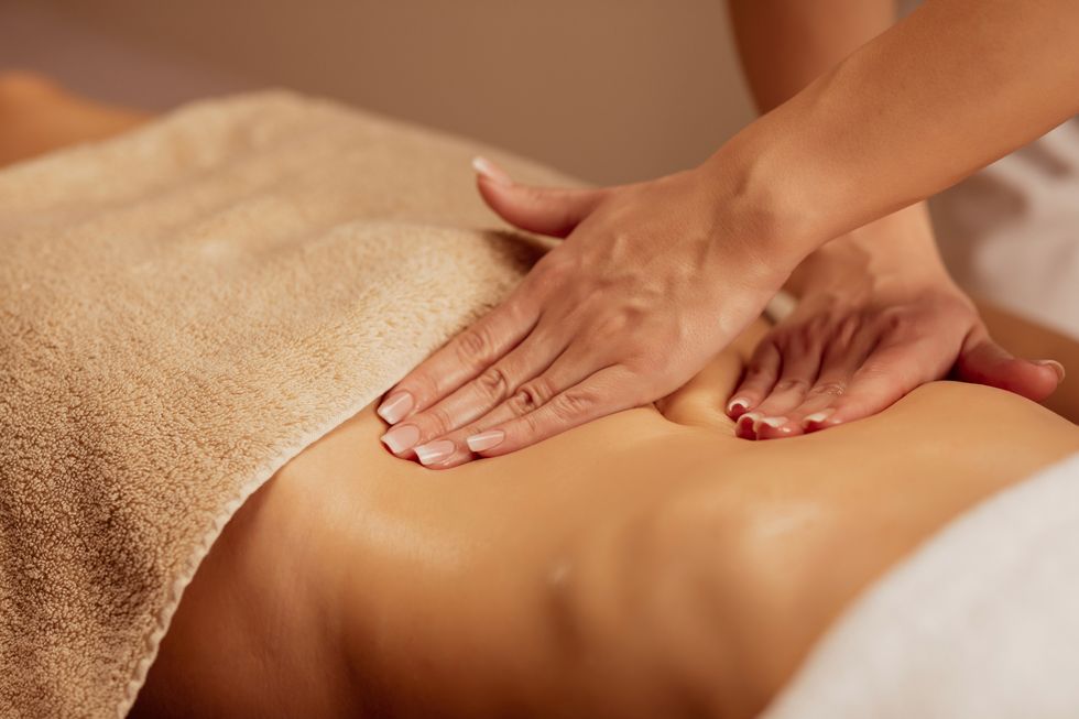 belly massage anti cellulite massage  massage therapist doing healing massage with rolling pin or battledore  woman enjoying in relaxing massaging at health spa treatment