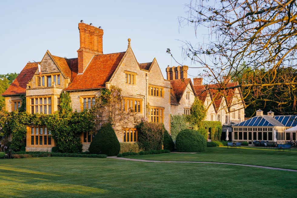 Food holidays belmond le manoir, oxfordshire a large brick building with a lawn in front of it