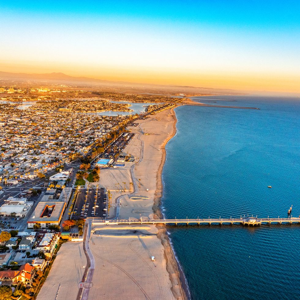 an aerial view of a town on a beach with a pier at sunset