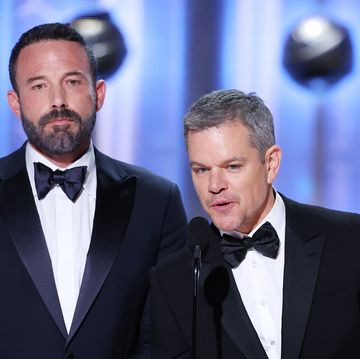 ben affleck and matt damon wear suits as they stand on a stage presenting an award