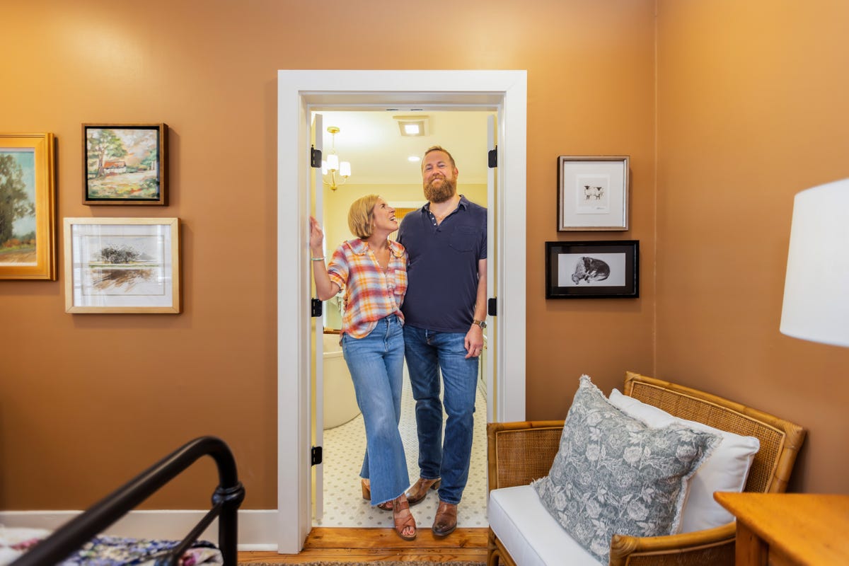 individuals standing in a doorway of a welldecorated room with artwork on the walls
