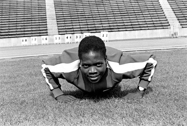 el atleta keniano ben jipcho haciendo una flexión en la hierba para una sesión fotográfica