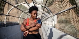benefits of eating after working out healthy woman touching phone screen on armband before exercising outdoors african american woman in sports clothing using phone while exercising outdoors