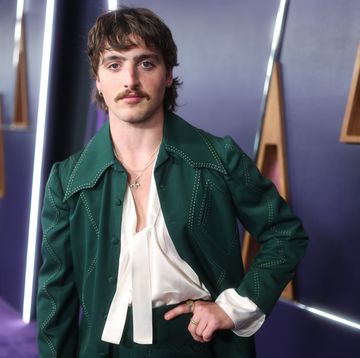 man wearing a green jacket and posing with his left hand on his hip