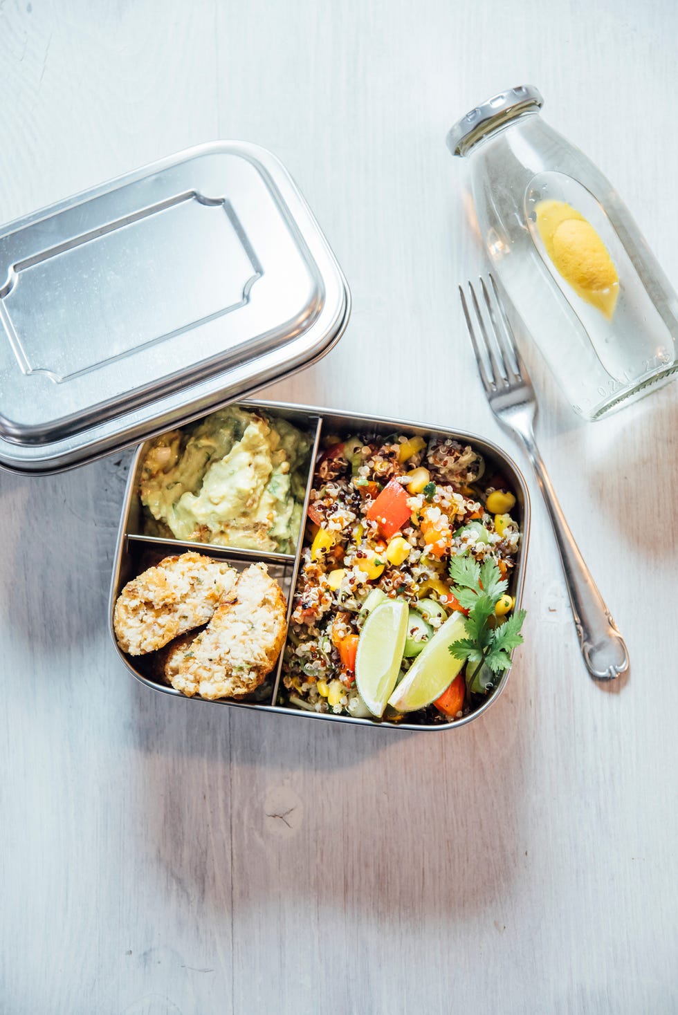 bento box of quinoa salad with vegetables and lime, avocado cream and cauliflower dumplings