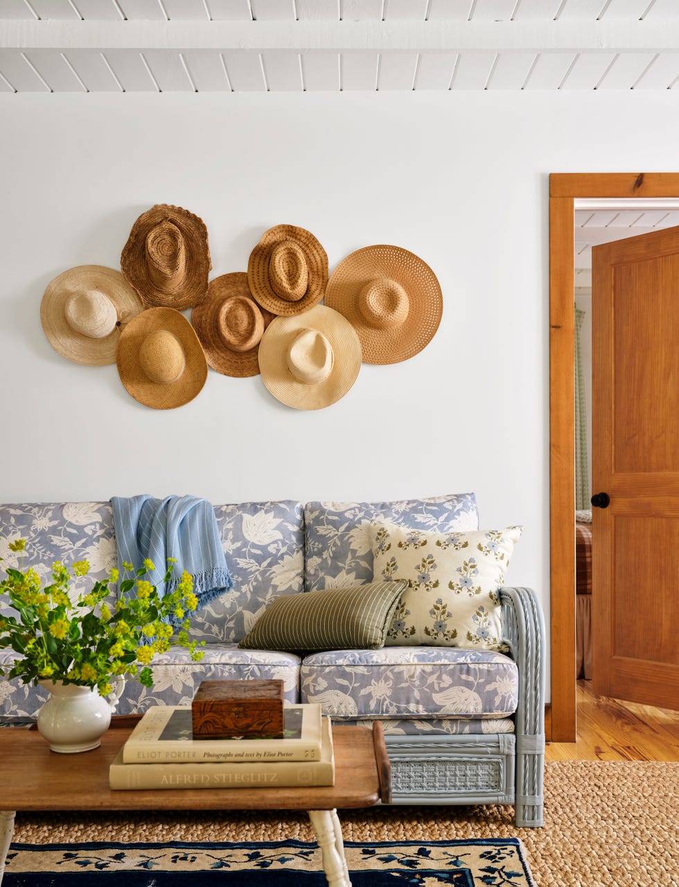 living room featuring a couch with a blue floral fabric and a collection of straw hats on the wall
