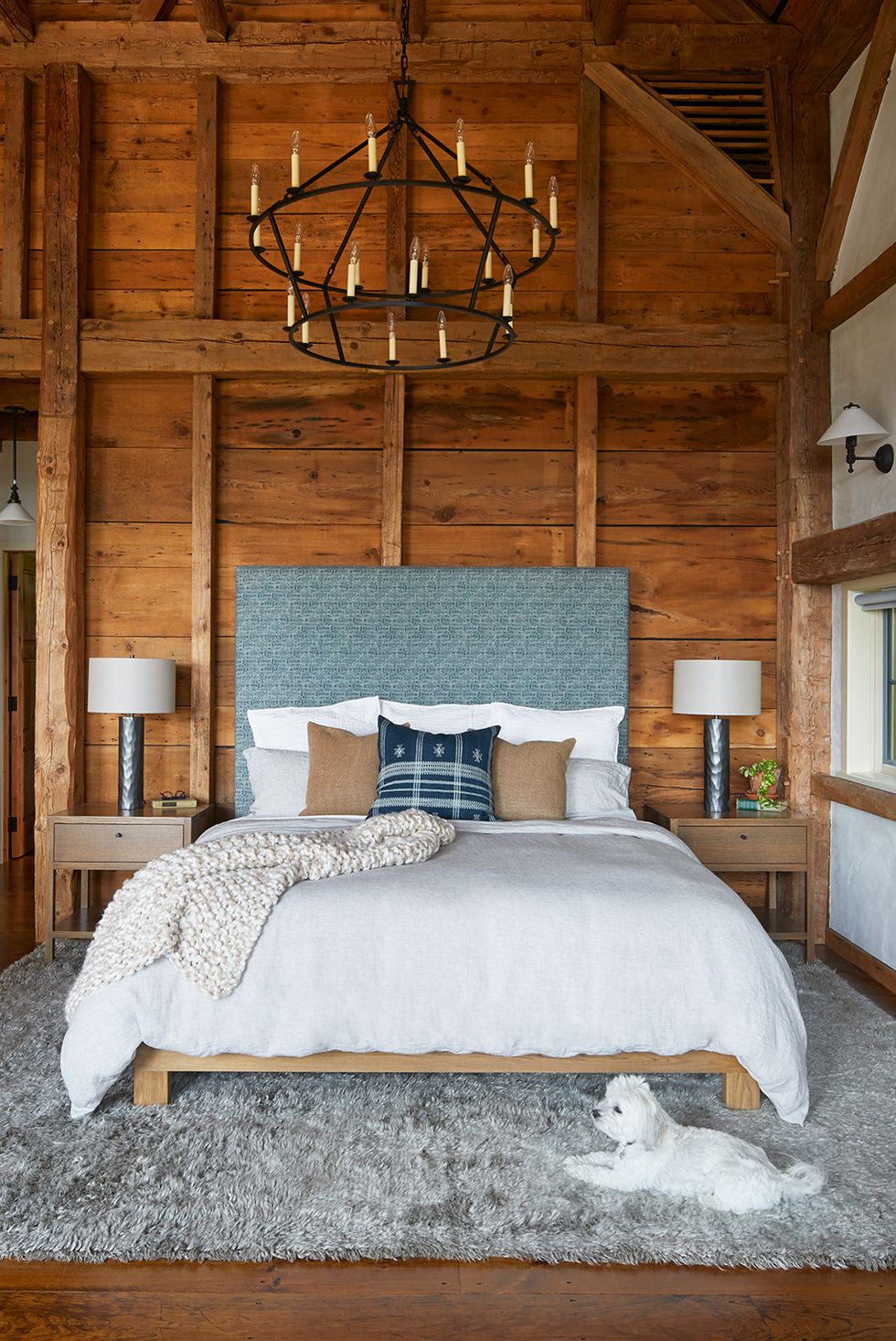 Bed with blue headboard and wood paneled walls
