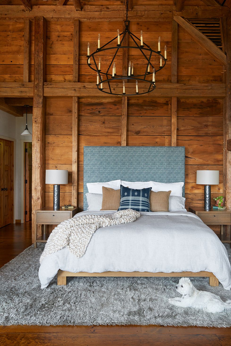 a bed with a blue headboard and wood paneling walls