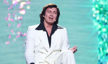 a person in a white suit seated with a confident posture