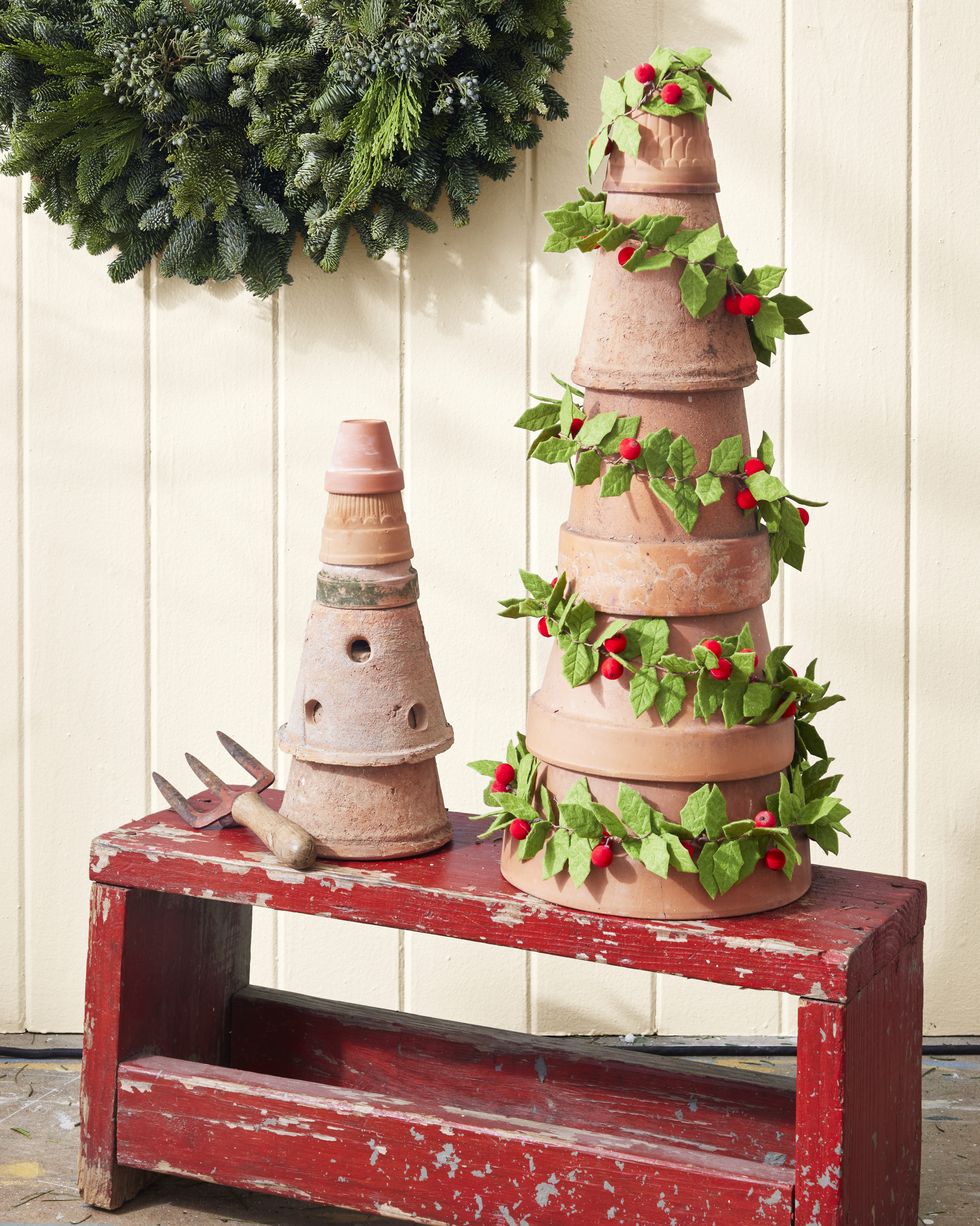 terra cotta pots stack to look like a christmas tree wrapped with a holly garland