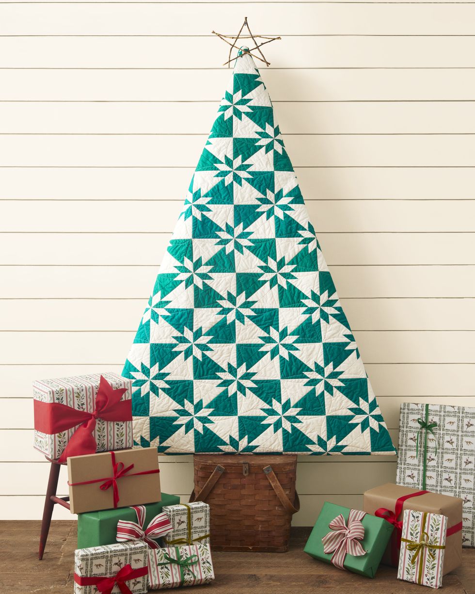 a christmas tree made from a green and white quilt set on a wicker picnic basket