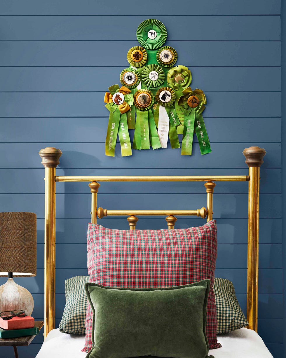 gree prize ribbons attached to a blue wall in the shape of a tree above a brass bed
