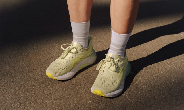 a pair of legs on a pavement wearing some yellow running shoes