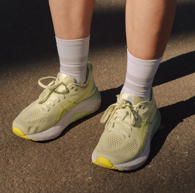 a pair of legs on a pavement wearing some yellow running shoes a pair of legs on a pavement wearing some yellow running shoes