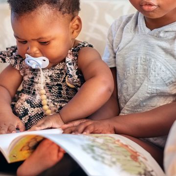 baby and brother reading together in chair