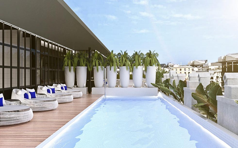a rooftop pool with chairs and a deck
