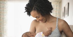 mum breastfeeds newborn baby at home
