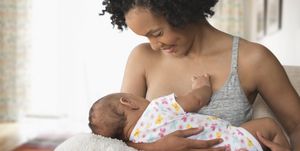 mum breastfeeds newborn baby at home