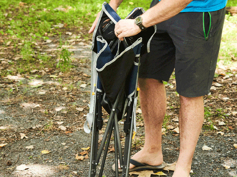 a person opening and placing a camping chair outside